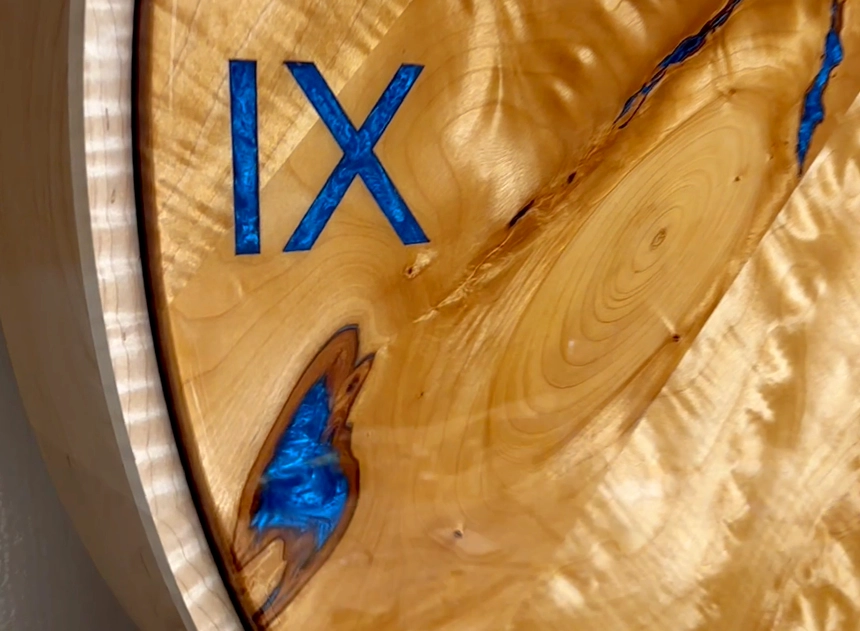 Opalescent blue epoxy filling hand-carved Roman numerals and natural voids in a wood clock face